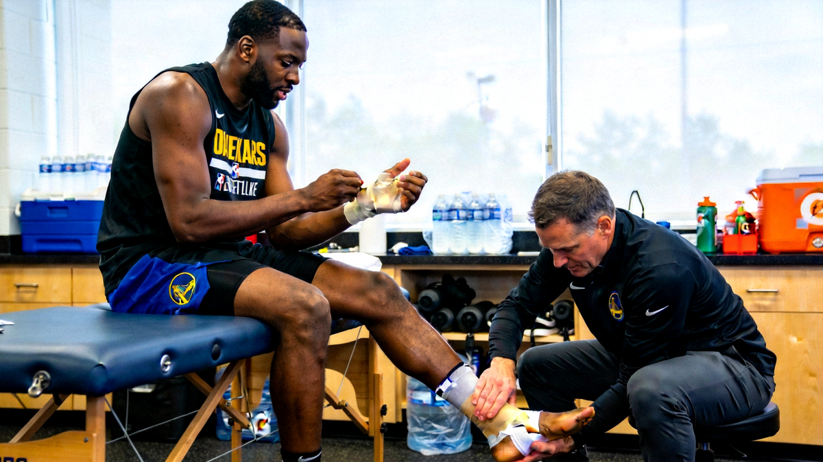 NBA球员在训练师陪同下进行康复训练，重点展示手腕和脚踝的包扎与检查场景